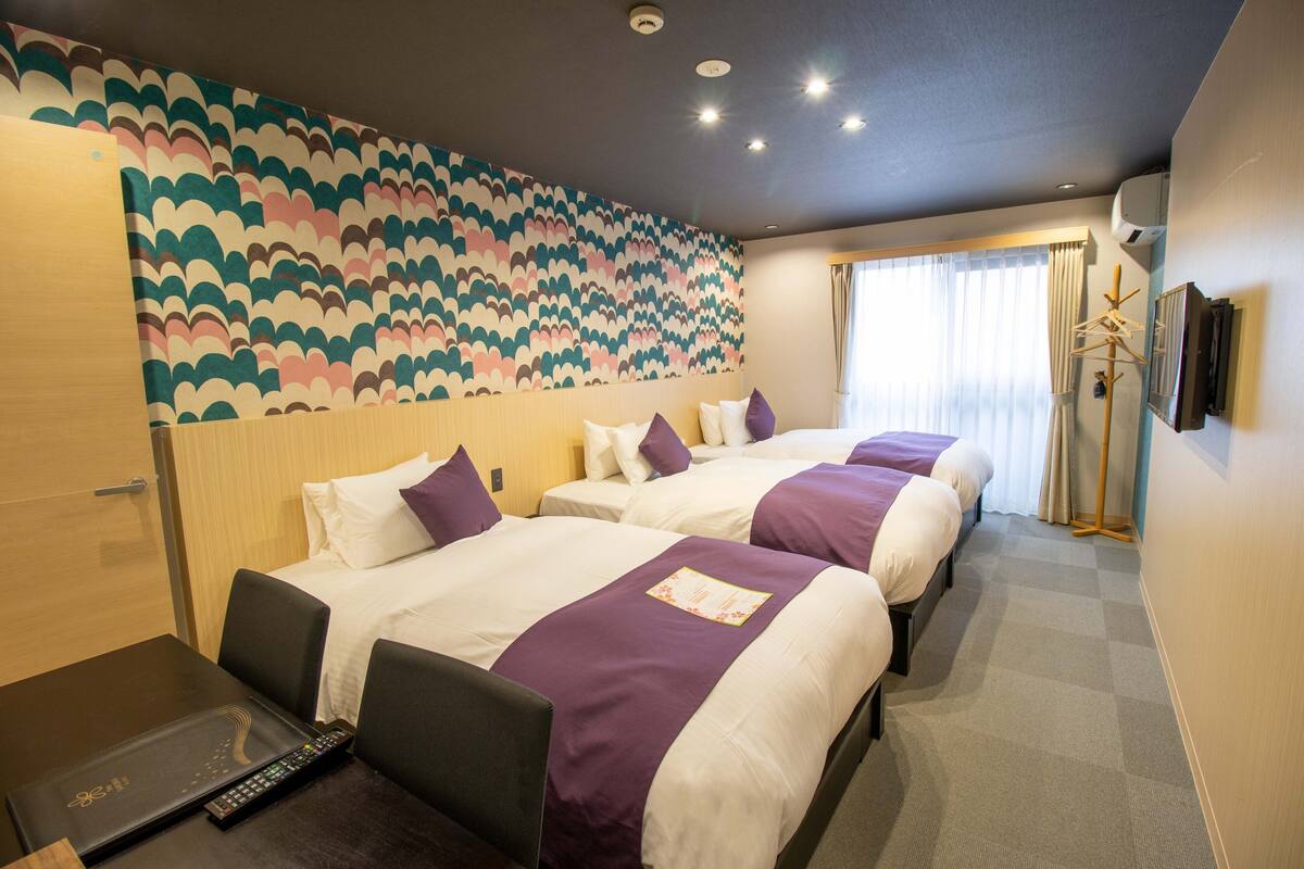 Una habitación de hotel con dos camas, un escritorio y una computadora portátil.