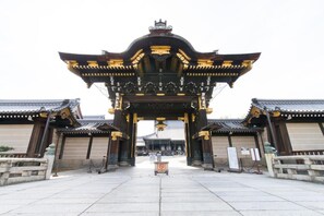 A traditional Japanese gate with a symmetrical design, featuring ornate golden decorations and a central lantern. - Stay SAKURA Kyoto ZEN (Kyoto)