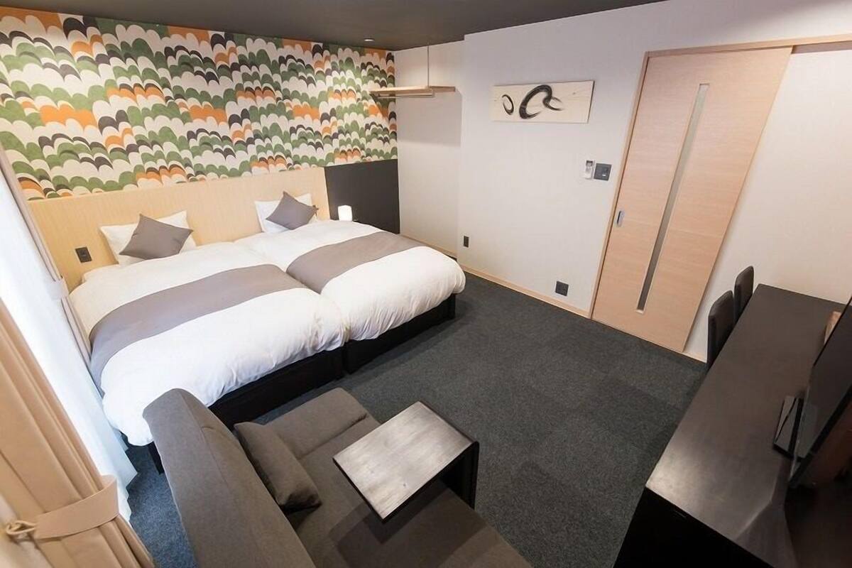 Una habitación de hotel con una cama grande, un sofá, una mesita y un escritorio.