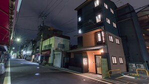 Un immeuble à plusieurs étages, doté d’une entrée fermée par un portail, d’un garage visible et situé dans une rue où les voitures sont garées.