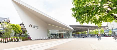 A modern building with a unique angular design, a covered entrance area, and a paved walkway.