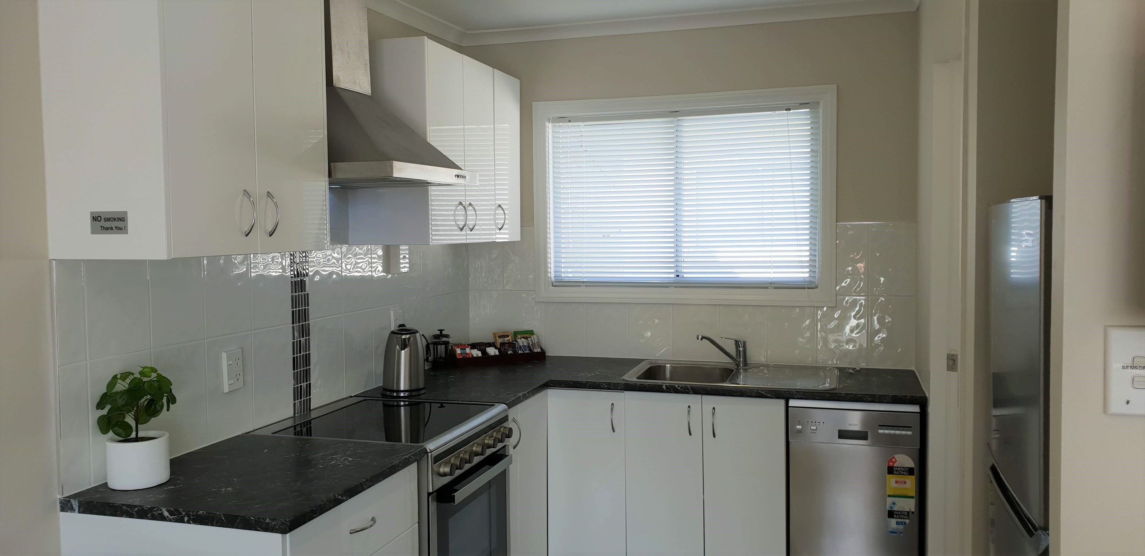 Een moderne keuken met witte kasten, een roestvrijstalen spoelbak en een inbouwoven.