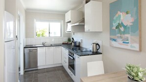 A modern kitchen with white cabinetry, a built-in oven, and a window.