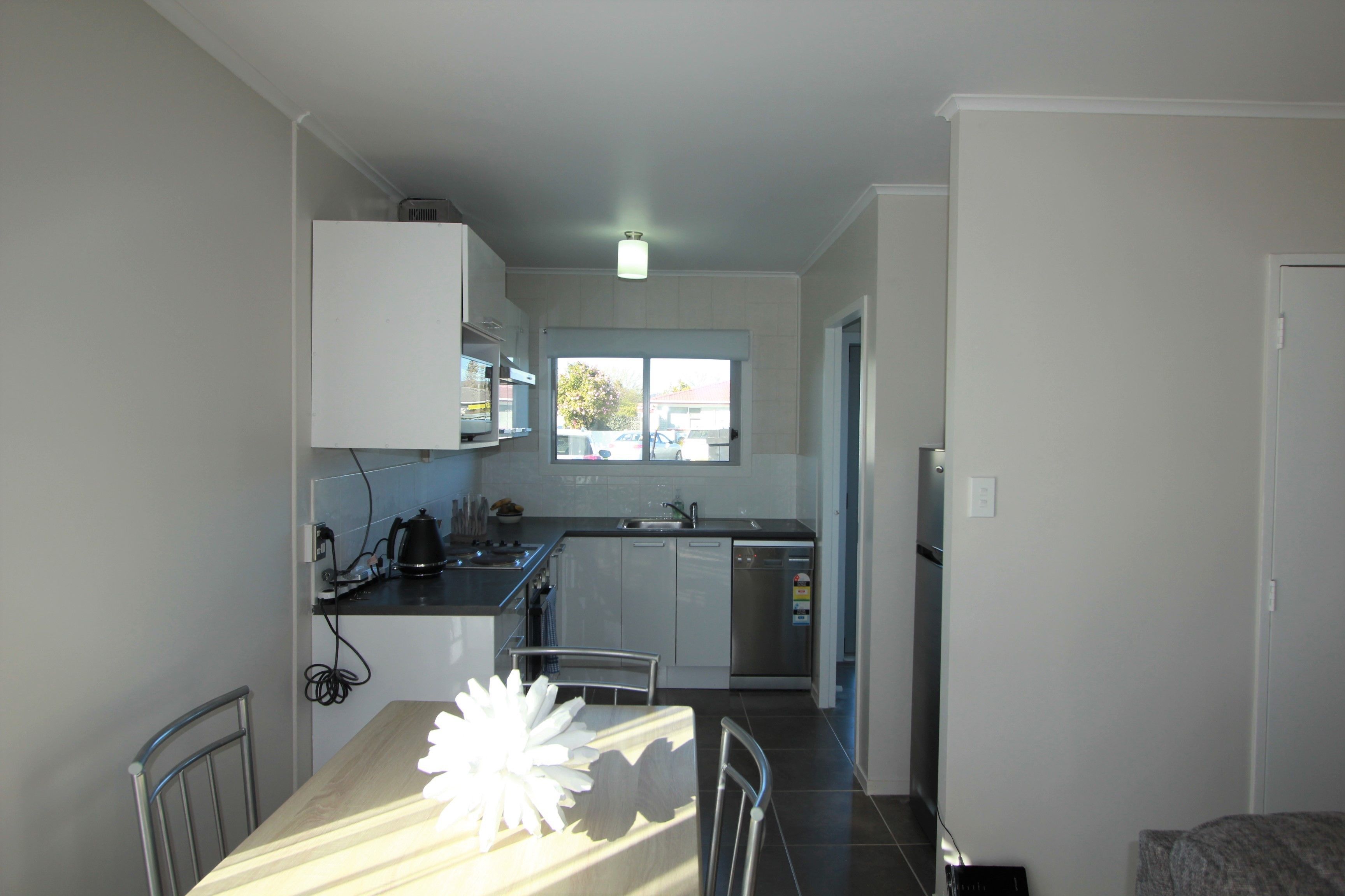 A compact kitchen with a dining area, featuring a table with a decorative centerpiece, a built-in oven, and a window providing natural light.