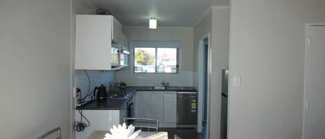 A compact kitchen with a dining area, featuring a table with a decorative centerpiece, a built-in oven, and a window providing natural light.