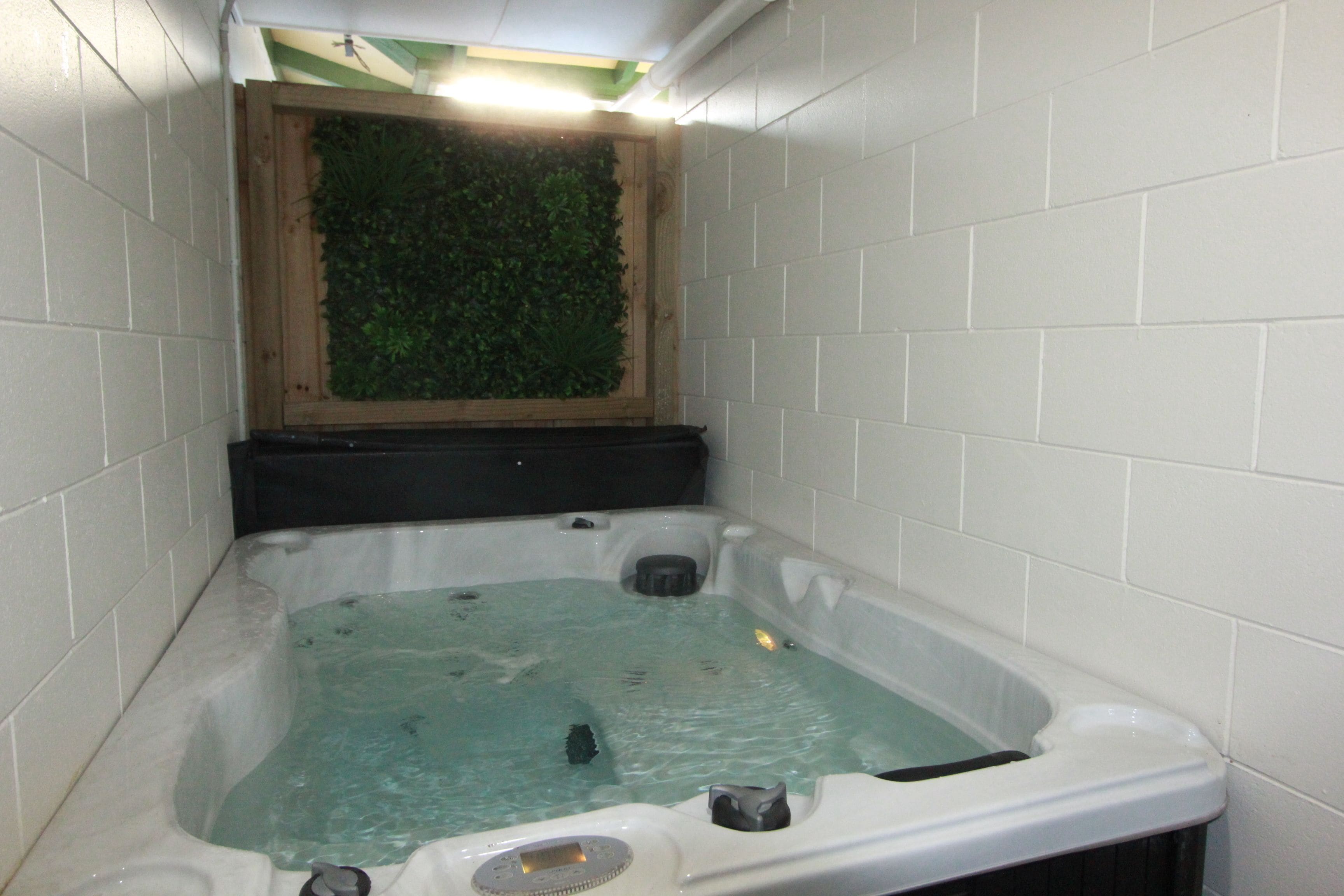 A hot tub with a wooden frame and a green wall behind it.