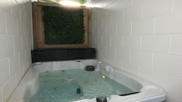 A hot tub with a wooden frame and a green wall behind it.