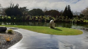 A park with a pond, a concrete path, and a statue.