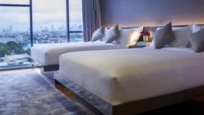 Una habitación de hotel con dos camas, vistas a la ciudad y un diseño moderno.