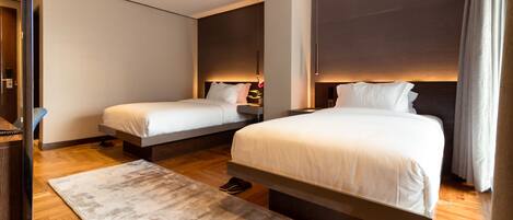 A modern hotel room with two single beds, a large window, and a wooden floor.