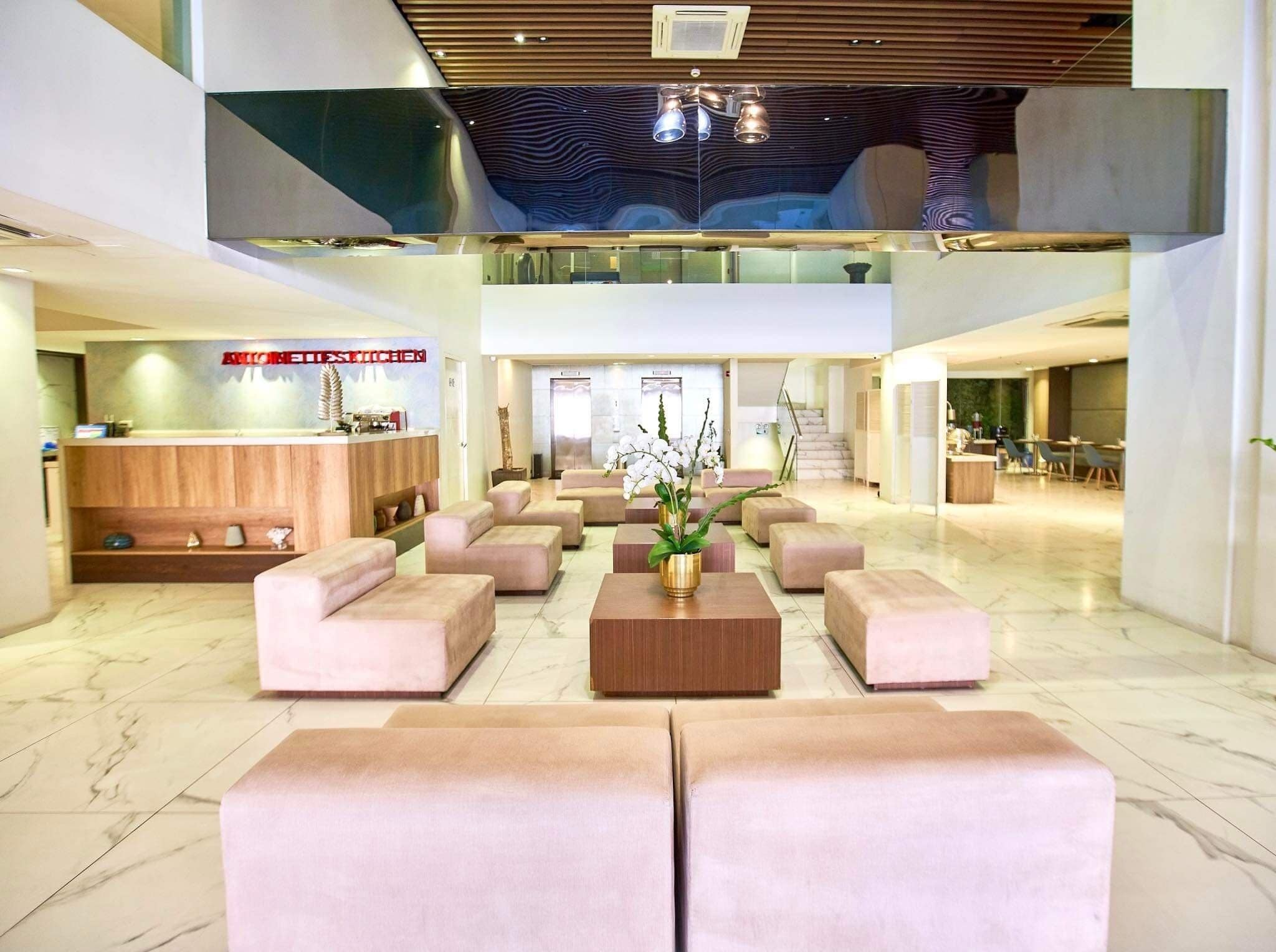 A spacious lobby with a reception desk, seating area, and a staircase leading to an upper level.