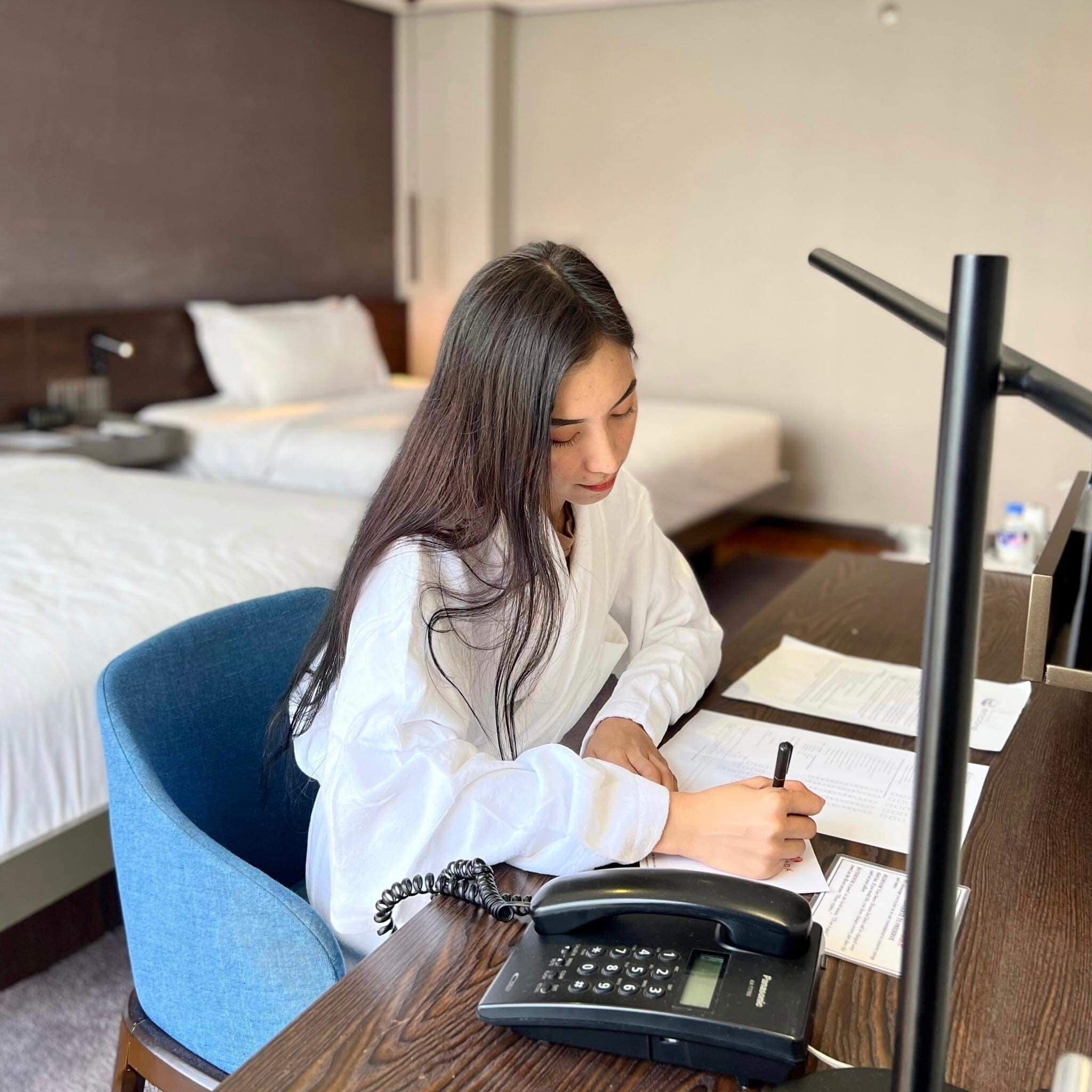 Ein Hotelzimmer mit einem Bett, einem Schreibtisch mit Telefon und einem Sessel.