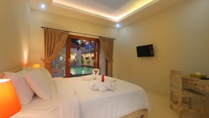 Habitación de hotel con cama, escritorio, televisor y vista al área de piscina exterior.