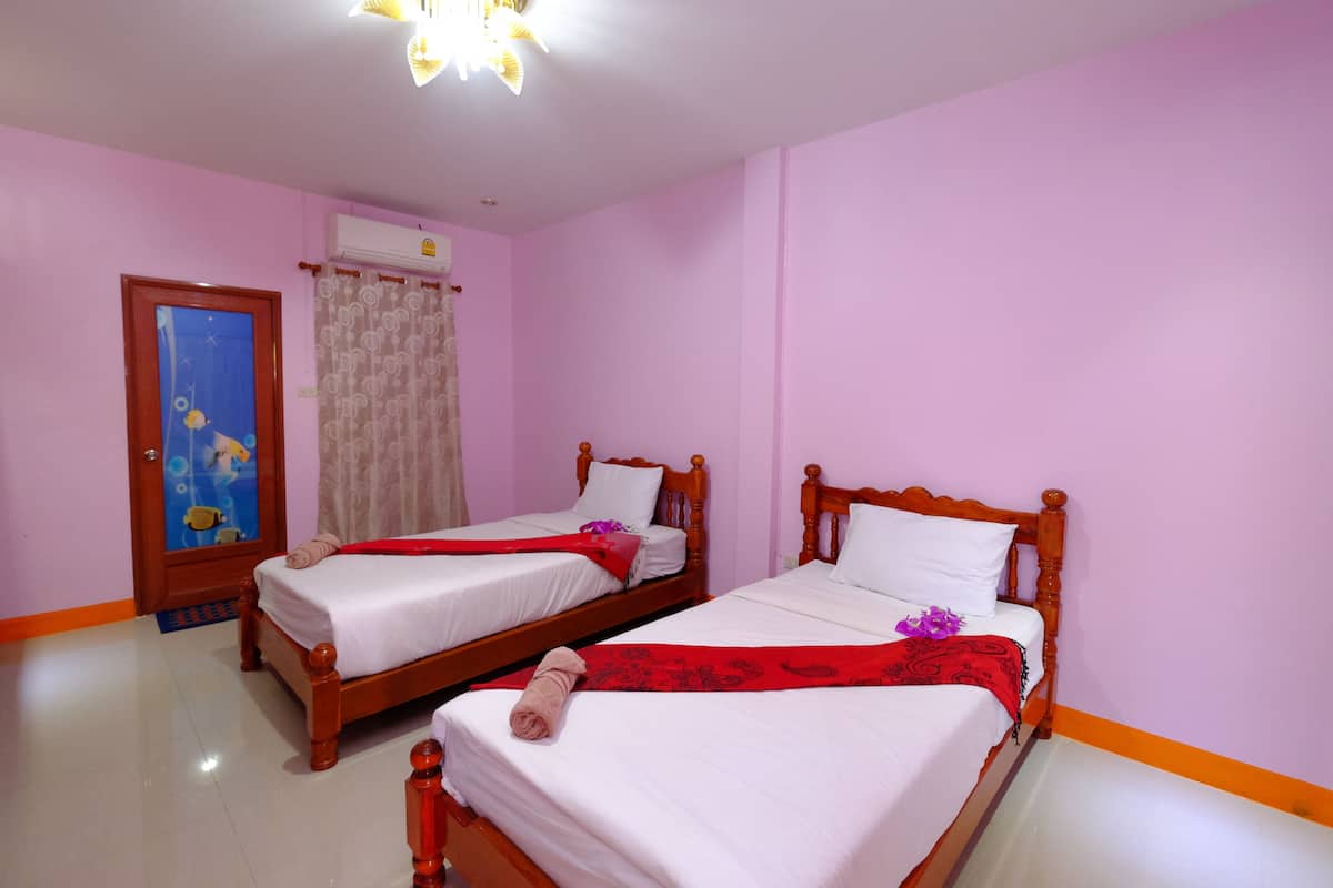 A hotel room with two wooden beds, white linens, and a red decorative item on each bed.
