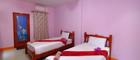 A hotel room with two wooden beds, white linens, and a red decorative item on each bed.