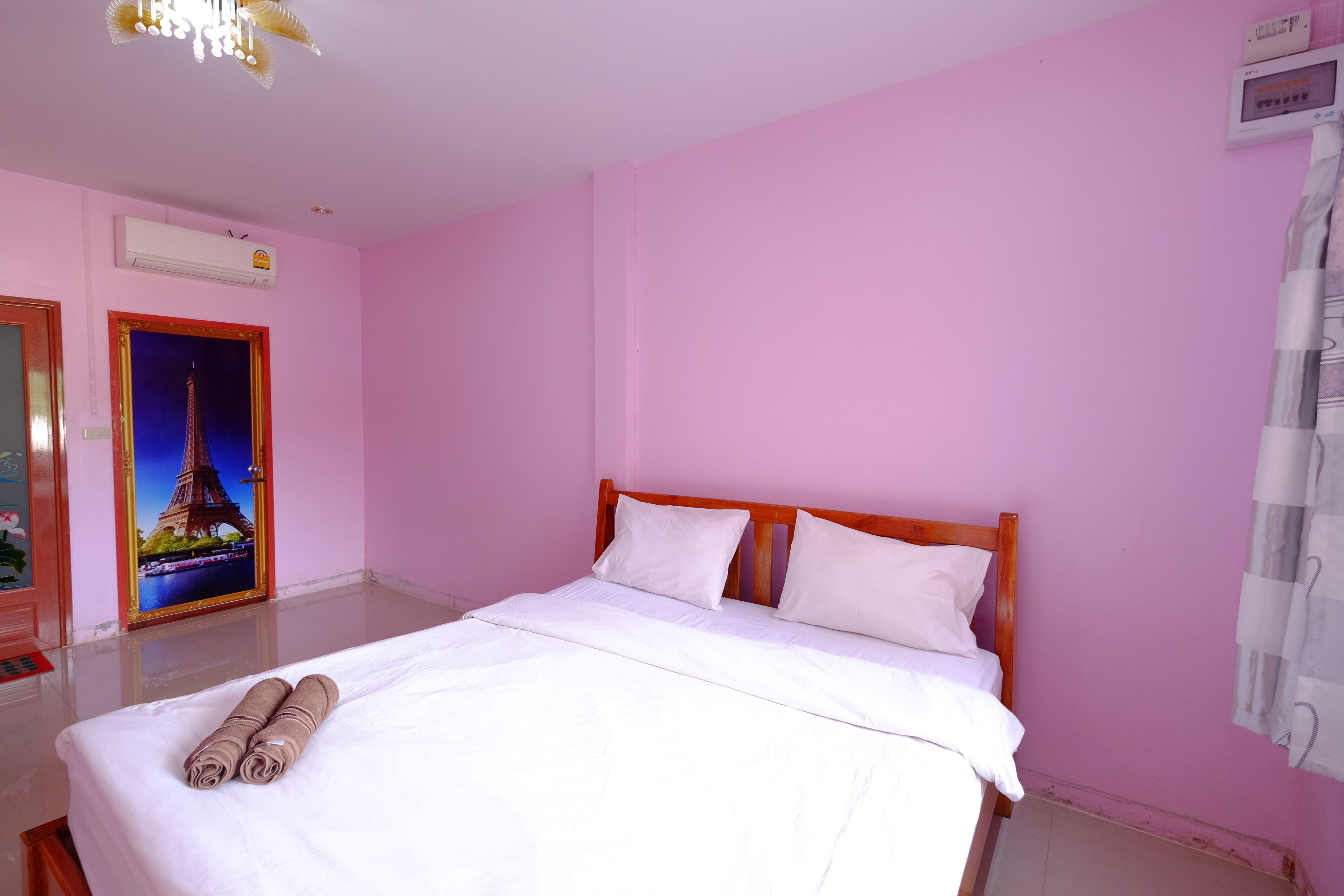 Habitación de hotel con cama, un cuadro de la Torre Eiffel, un termostato y una cortina.