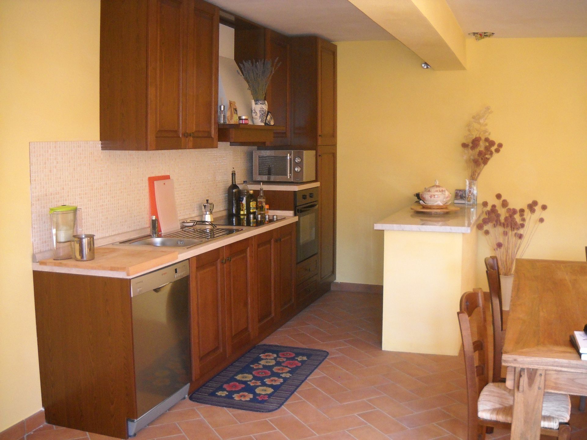 A compact kitchen with wooden cabinets, a microwave, and a small dining area with a table and chairs.