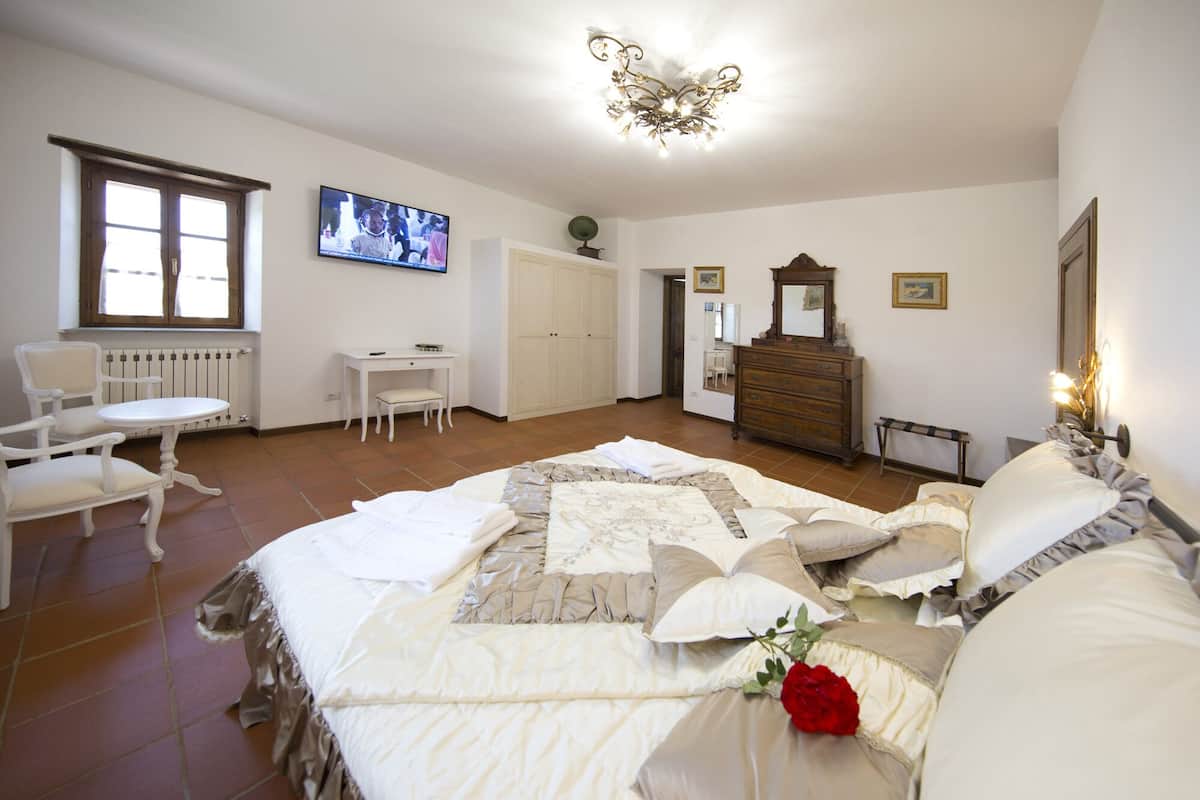 A bedroom with a bed, a desk, a chair, a dresser, and a television.