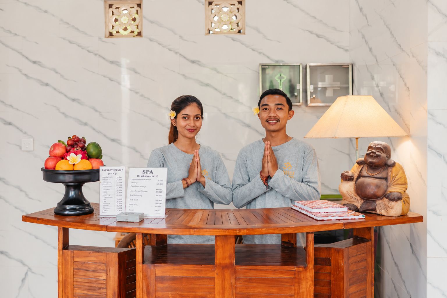 Un mostrador de recepción con un frutero, un menú de spa y una estatua.