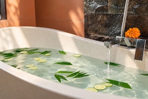 Una bañera con agua, rodajas de lima y hojas verdes.