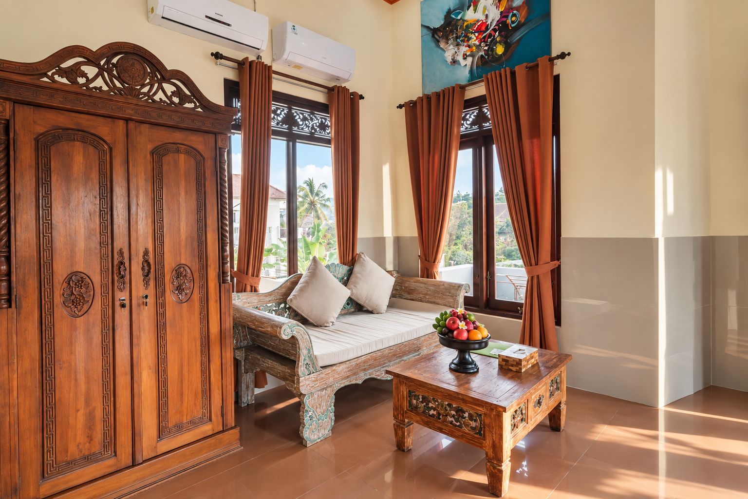 A room with a wooden cabinet, a sofa, a coffee table with fruit, and a view of palm trees through the window.