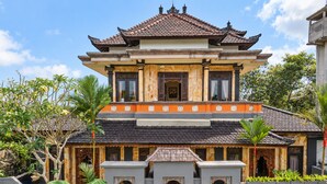 A traditional multi-story building with a tiled roof, ornate wooden doors, and a symmetrical facade. - Grand Ashanti Villa (Ubud)