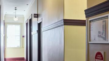 A hotel corridor with a fire extinguisher, an evacuation diagram, and a sign indicating a men's and women's restroom.