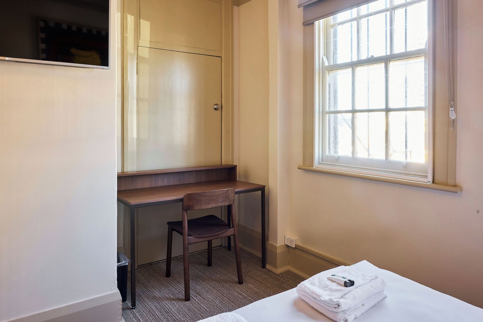 A small room with a desk, chair, and a window.