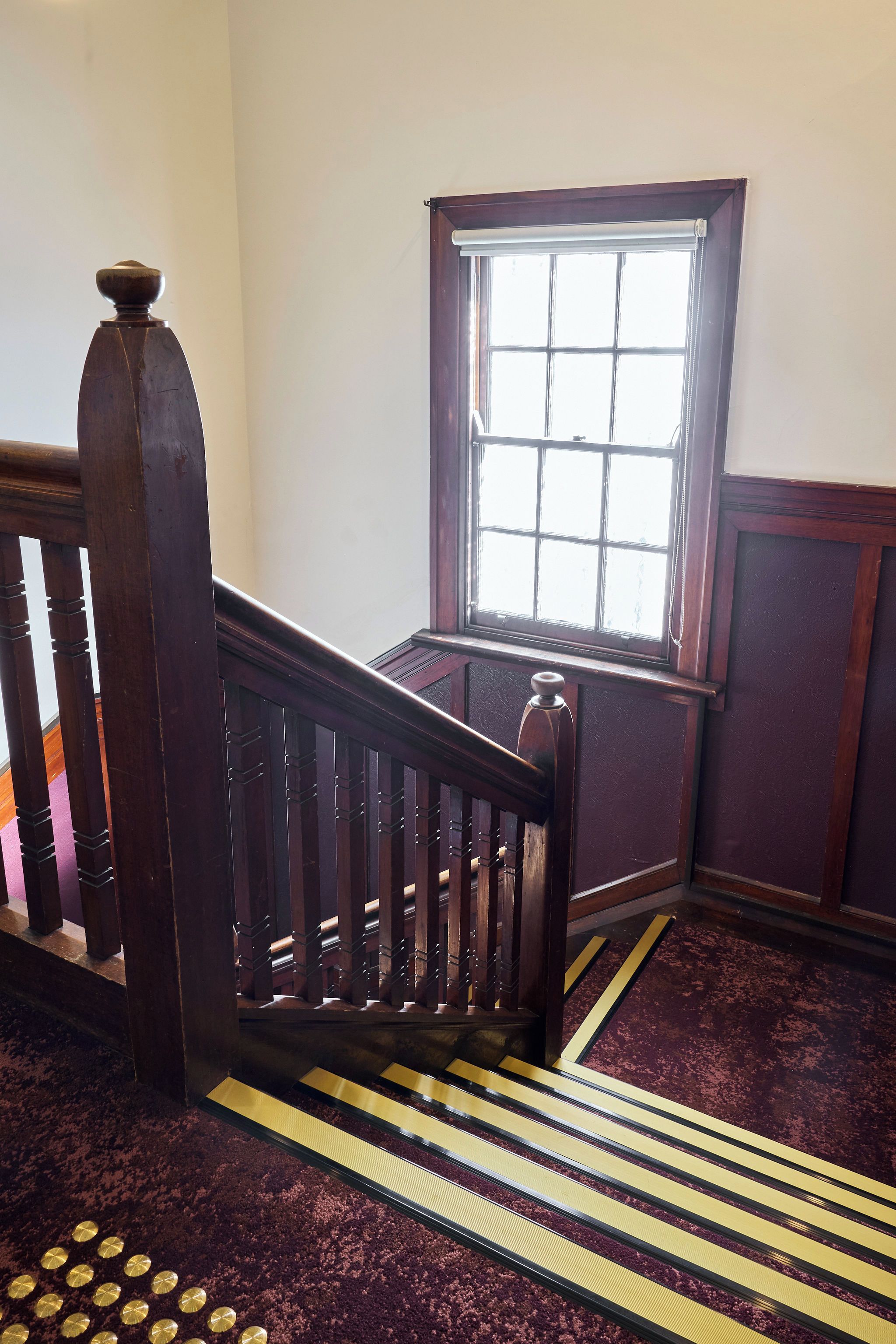 A wooden staircase with a handrail and a window with a grid pattern.