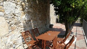 A stone wall with a wooden table and chairs set up outdoors. - O Cruceiro (Boiro)