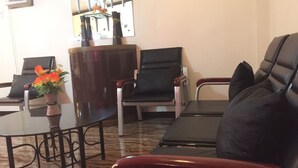 A seating area with a sofa, two chairs, a small table, and a vase with flowers. - Summer Splash Resort (Gingoog)