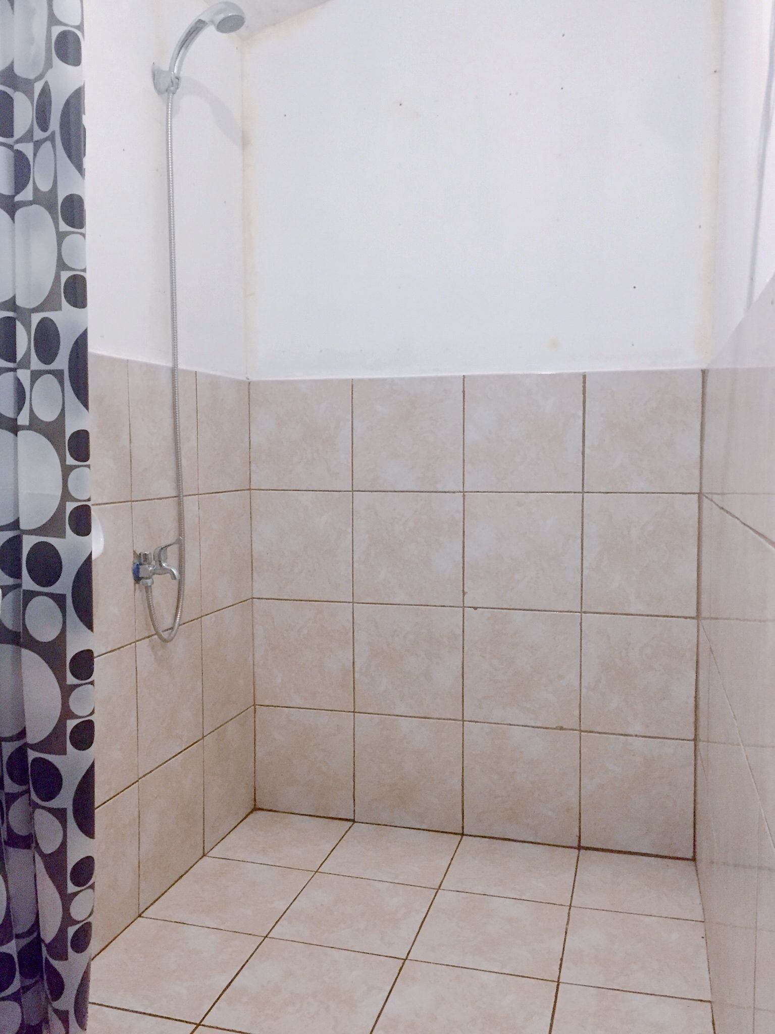 Un espacio de ducha pequeño con azulejos, un cabezal de ducha y un grifo.