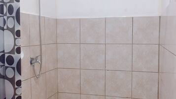 Un espacio de ducha pequeño con azulejos, un cabezal de ducha y un grifo.