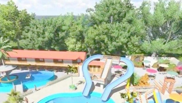 A water park with multiple pools and slides, surrounded by palm trees and a building in the background. - Summer Splash Resort (Gingoog)