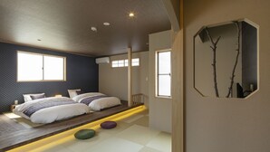 A modern bedroom with a large bed, a small seating area, and a unique wall-mounted mirror. - hisashi (Kyoto)