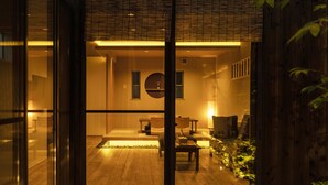 A modern interior with a wooden floor, a sofa, a table, and a decorative plant. - hisashi (Kyoto)