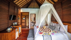 A wooden room with a bed, a TV, and a desk. - D'Puncak Villas Lembongan (Lembongan Island)