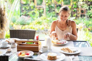 Disposição para o café da manhã com uma mesa posta para dois, incluindo pratos com comida, xícaras e uma cesta.