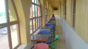 Un pasillo con mesas y sillas, ventanas amplias y vistas al exterior.