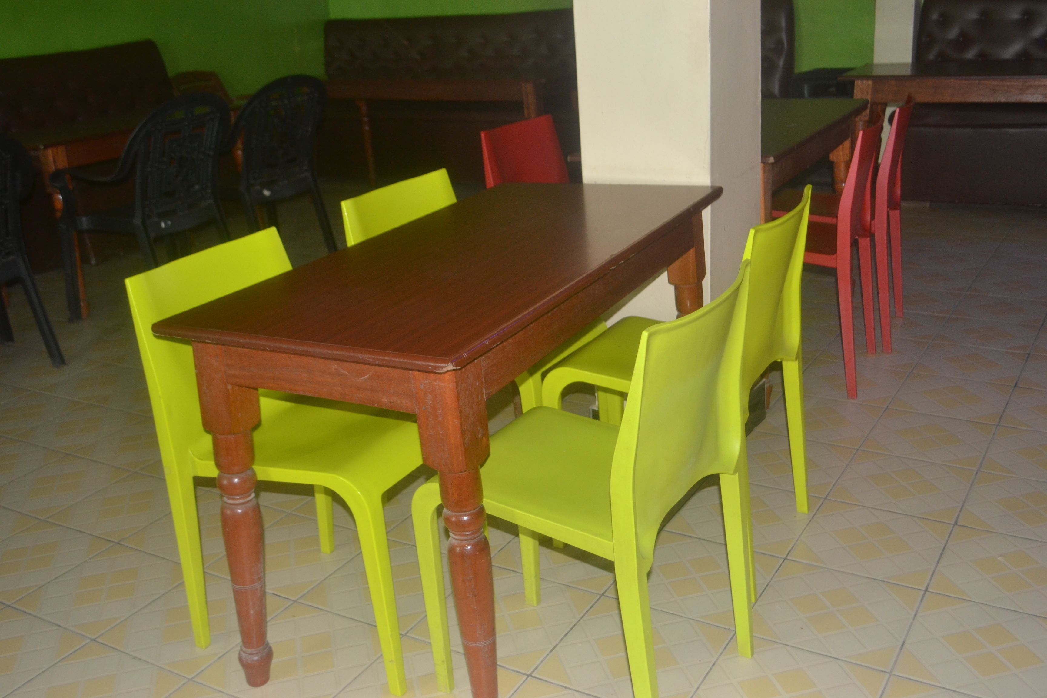 A dining area with a wooden table and chairs, some with bright yellow and red upholstery.