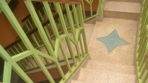 Una escalera con barandillas verdes y un marcador en el suelo con forma de estrella.