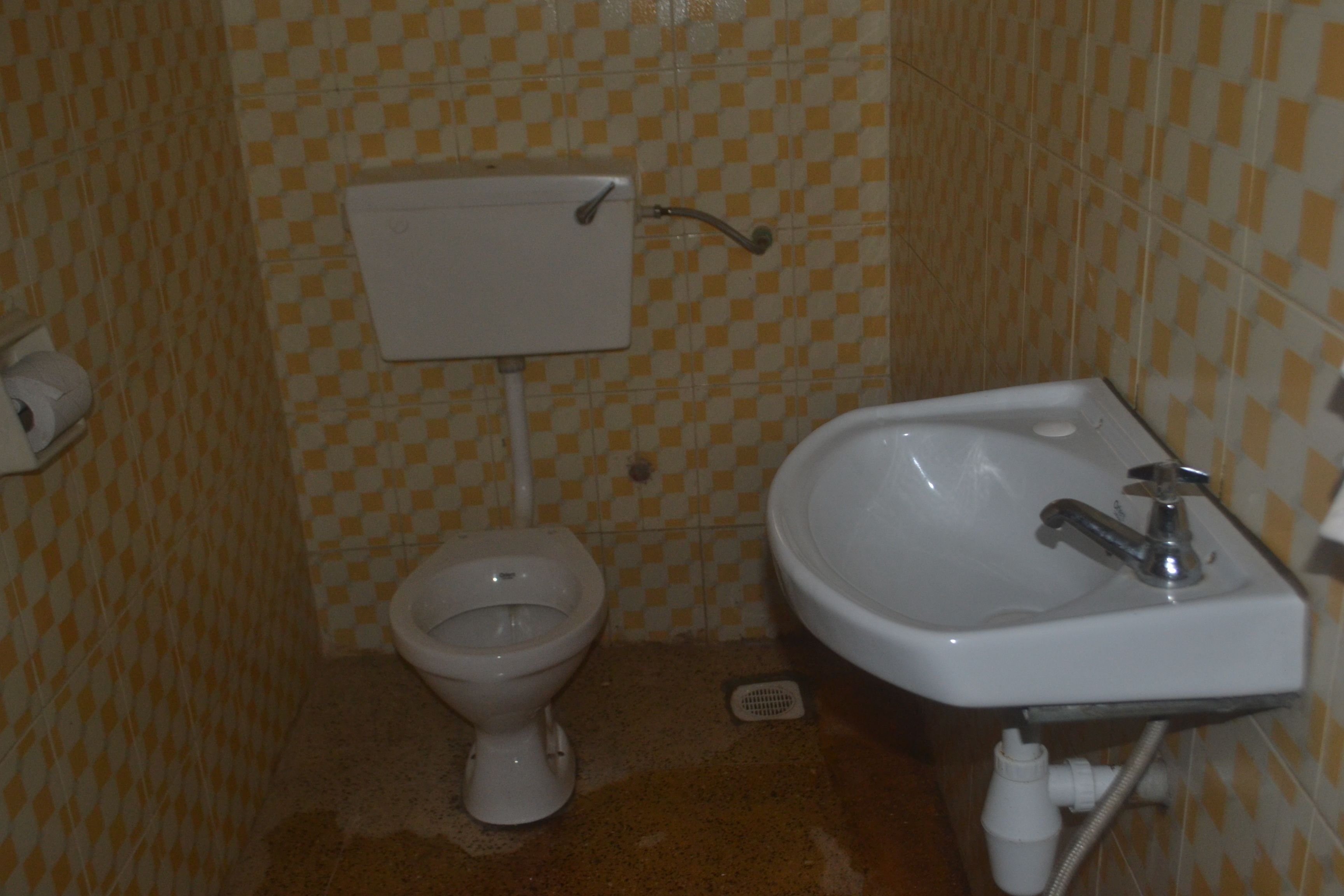 Une salle de bain avec un mur recouvert de carreaux à motifs géométriques, des toilettes et un lavabo avec un miroir.