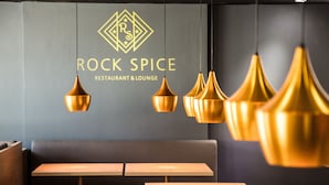 A restaurant with a modern interior, featuring a seating area with wooden tables and benches, and pendant lighting.