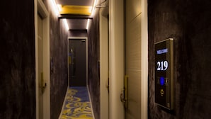 A hotel hallway with a patterned carpet, a welcome sign, and a door with a number.