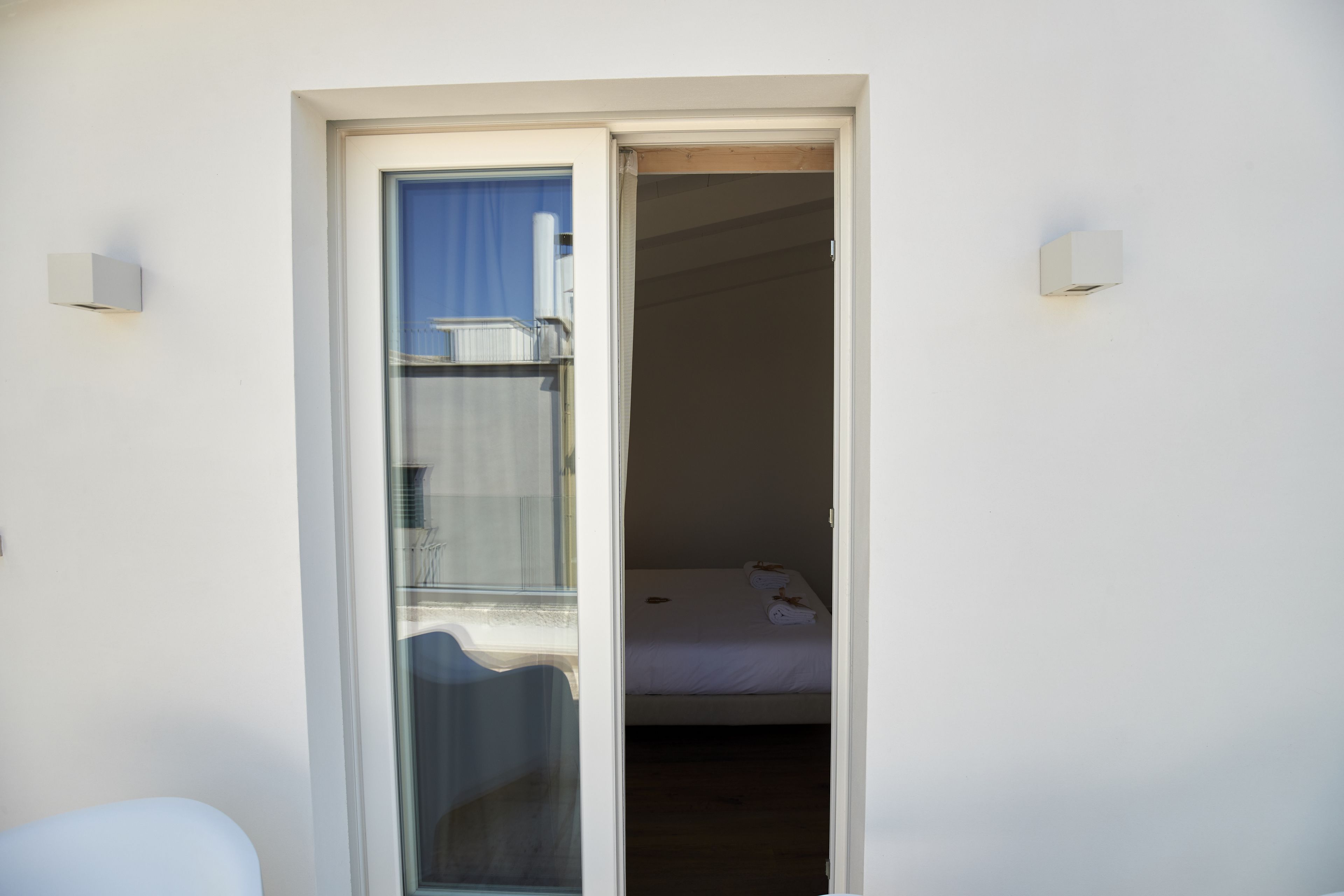A hotel room with a bed, a chair, and a window.