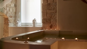 A serene spa area with a stone wall, a window with the inscription "21st century," and a small statue on the windowsill. - Iulius Suite & spa (Conversano)