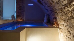 A stone-walled interior with a pool and steps leading to a higher level. - Iulius Suite & spa (Conversano)
