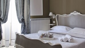 A bedroom with a bed, a radiator, a hanging light fixture, and a window with curtains. - Affittacamere Angel 2 (La Spezia)