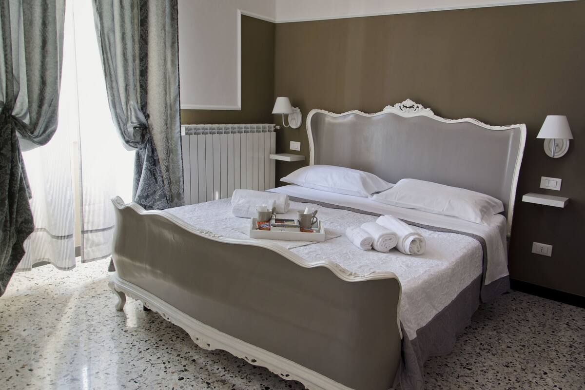 Un lit bien fait, avec une tablette contenant des articles de toilette, une tête de lit blanche et une lampe fixée au mur.
