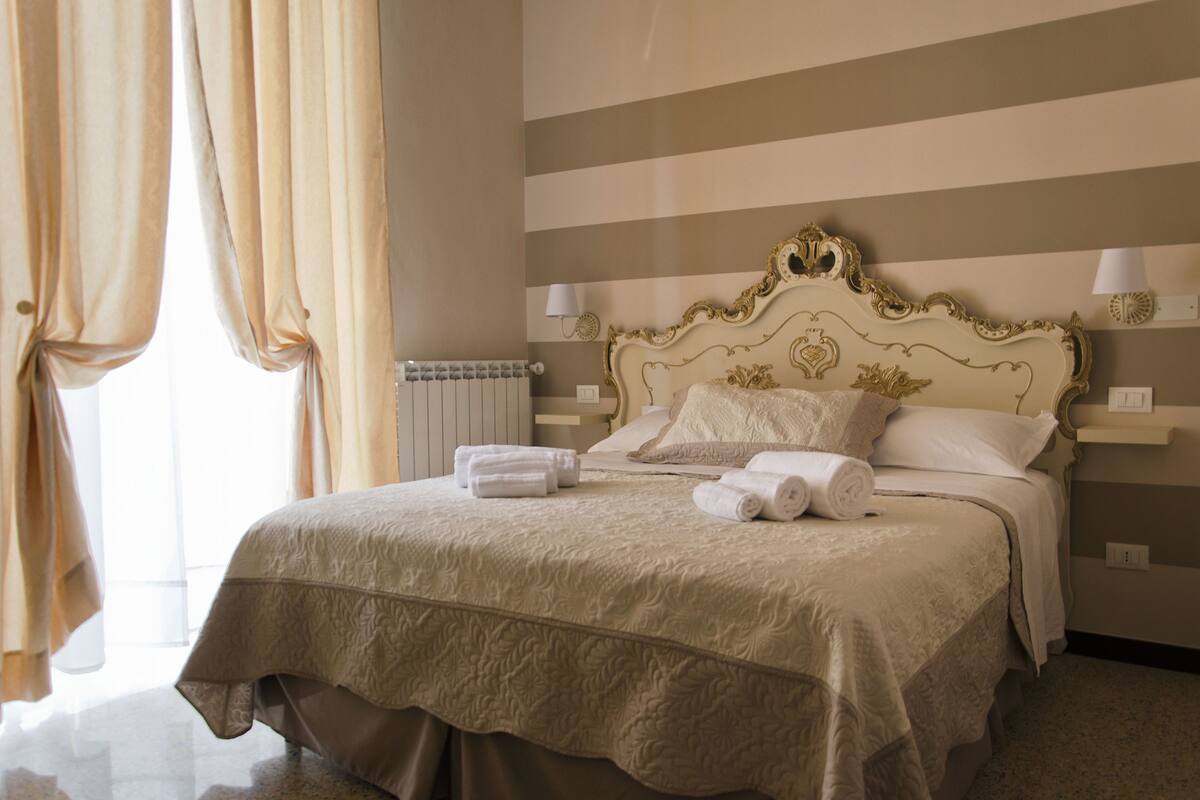 Une chambre d’hôtel avec un grand lit, un radiateur et des rideaux.